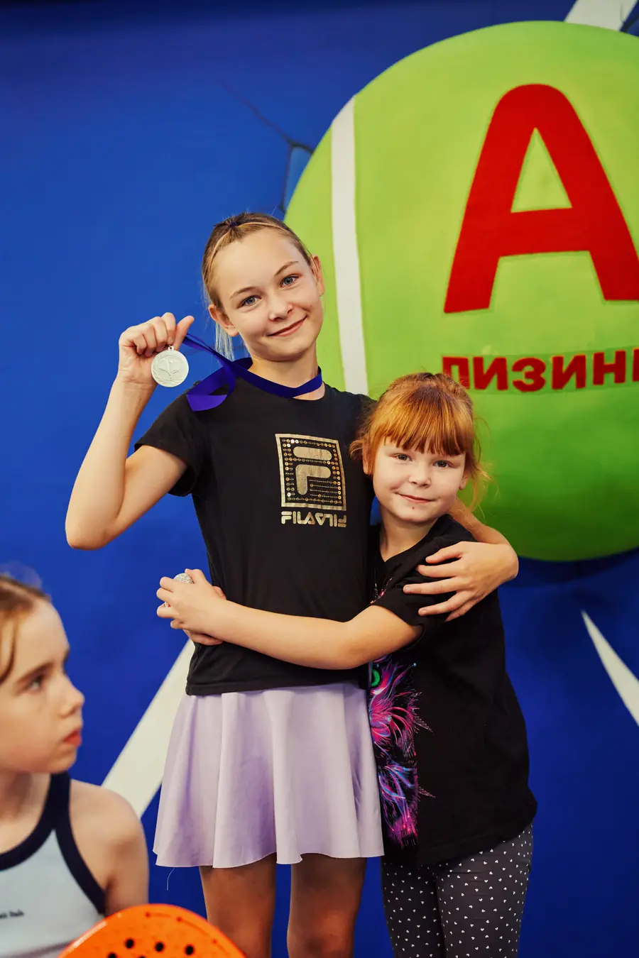 Победительница детского турнира с медалью обнимает подругу